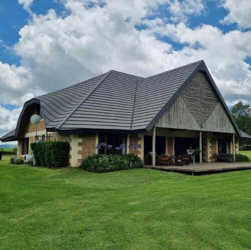 Plain Champagne Guest Farm Homestead Exterior Exterior view of the Plain Champagne Guest Farm homestead with thatched roof and wide green lawn in the Drakensberg